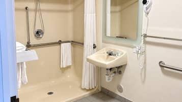 A bathroom with a walk-in shower, a sink with a mirror, and a toilet.