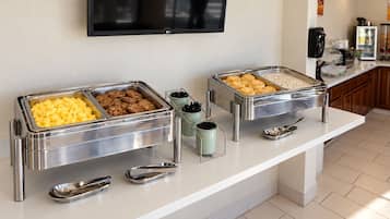 A buffet setup with various food items and serving utensils.