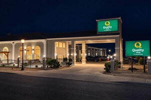 Un hotel Quality Inn con un letrero grande, un estacionamiento techado y una entrada bien iluminada.