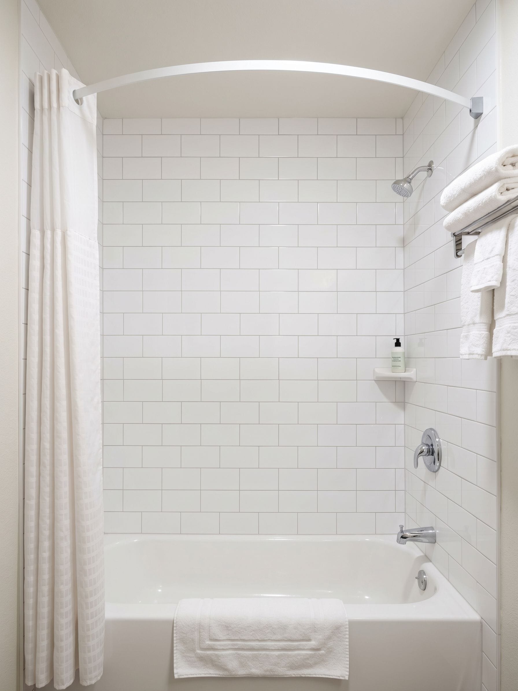A modern bathroom with a white bathtub, shower, and tiled walls.
