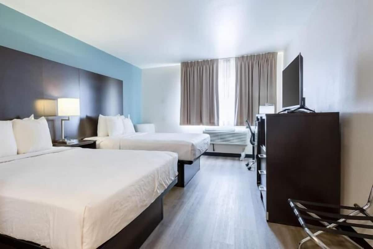 A hotel room with two beds, a desk, a TV, and a wardrobe.