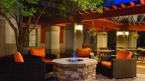 An outdoor seating area with wicker furniture and a stone fire pit. - HYATT house Denver Tech Center (Greenwood Village)