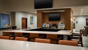 A conference room with a large table, chairs, a bar area with bottles, and a flat-screen TV mounted on the wall. - HYATT house Denver Tech Center (Greenwood Village)