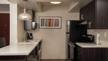 A modern kitchen with dark wood cabinets, a stainless steel refrigerator, and a pendant light.