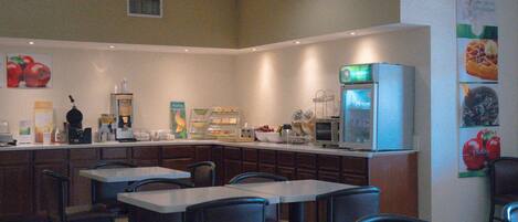 A restaurant with a counter, seating, and a refrigerator.