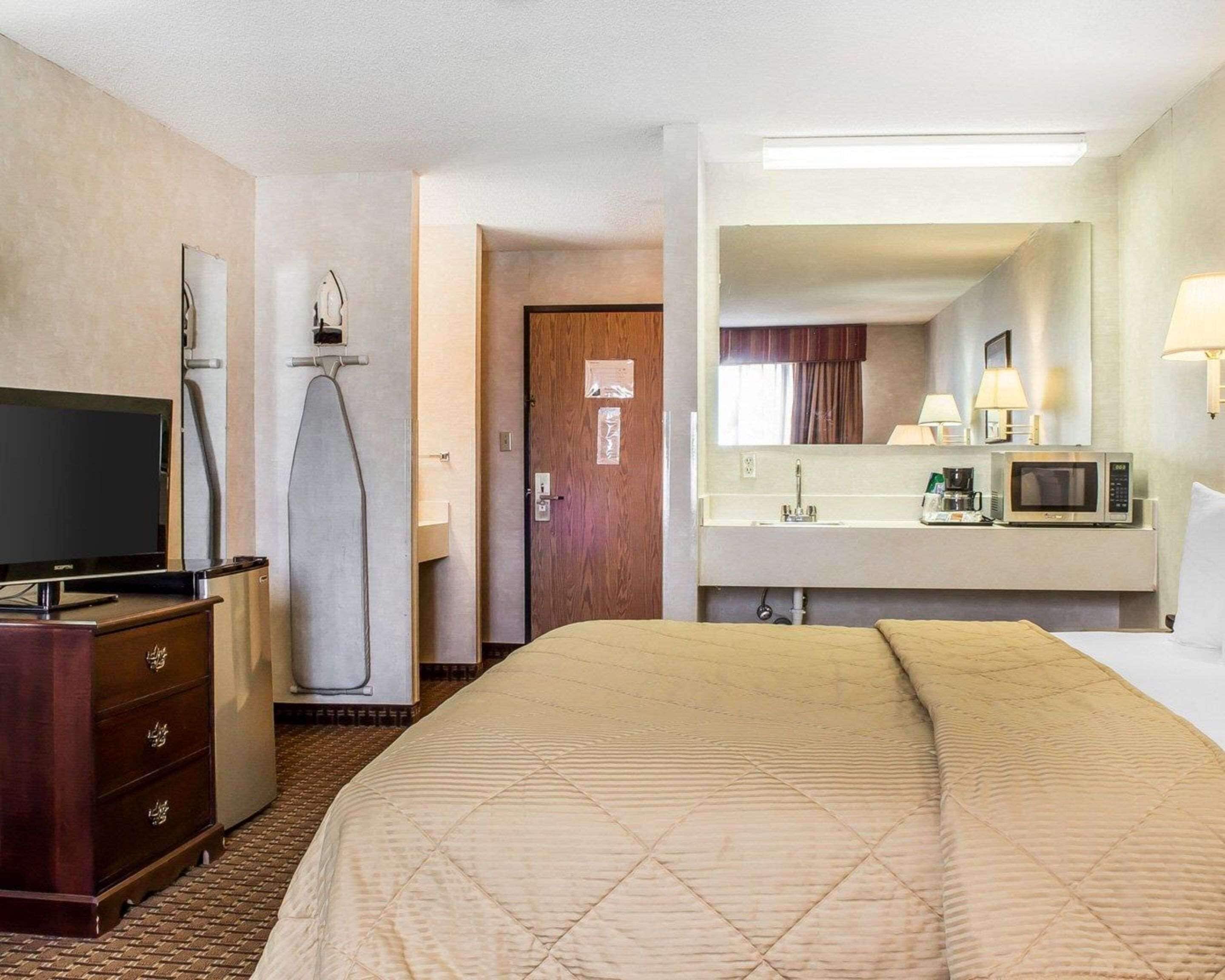 Une chambre d’hôtel équipée d’un lit, d’une télévision, d’un four à micro-ondes, d’un lavabo et d’un miroir.