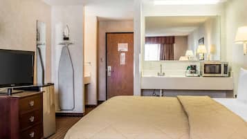 Une chambre d’hôtel équipée d’un lit, d’une télévision, d’un four à micro-ondes, d’un lavabo et d’un miroir.