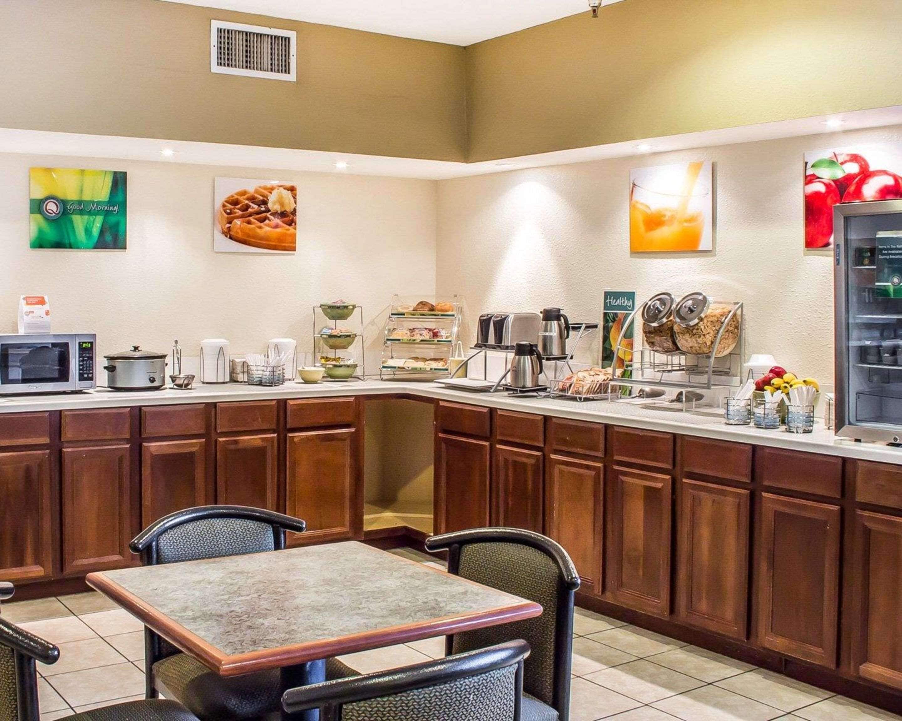 Una cocina de hotel con una barra de buffet, que incluye un microondas, una cafetera y diversos alimentos.