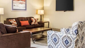 A living room with a sofa, armchair, coffee table, and a flat-screen TV mounted on the wall. - Quality Inn & Suites Yuma (Yuma)