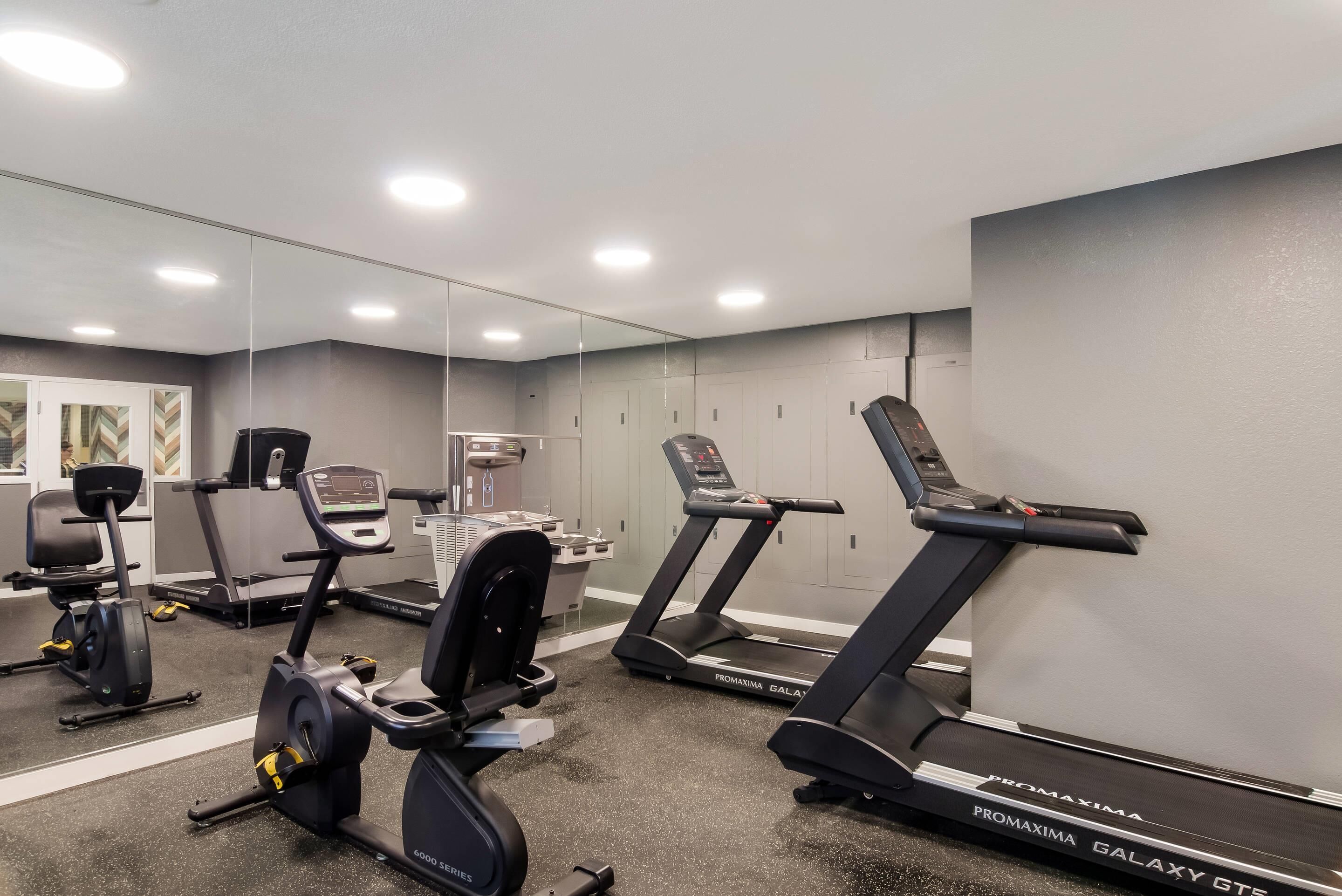 Un gimnasio con equipo de ejercicio, incluyendo cintas de correr y bicicletas estáticas.