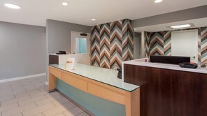 A reception desk with a glass top and wooden base, a computer, and a chevron-patterned wall. - MainStay Suites Denver Tech Center (Centennial)