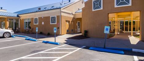 A parking lot with marked spaces and a building entrance with a ramp.