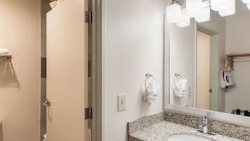 A bathroom with a granite countertop sink, a mirror, and a towel rack.
