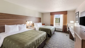 A hotel room with two beds, a TV, a desk, and a window with curtains.