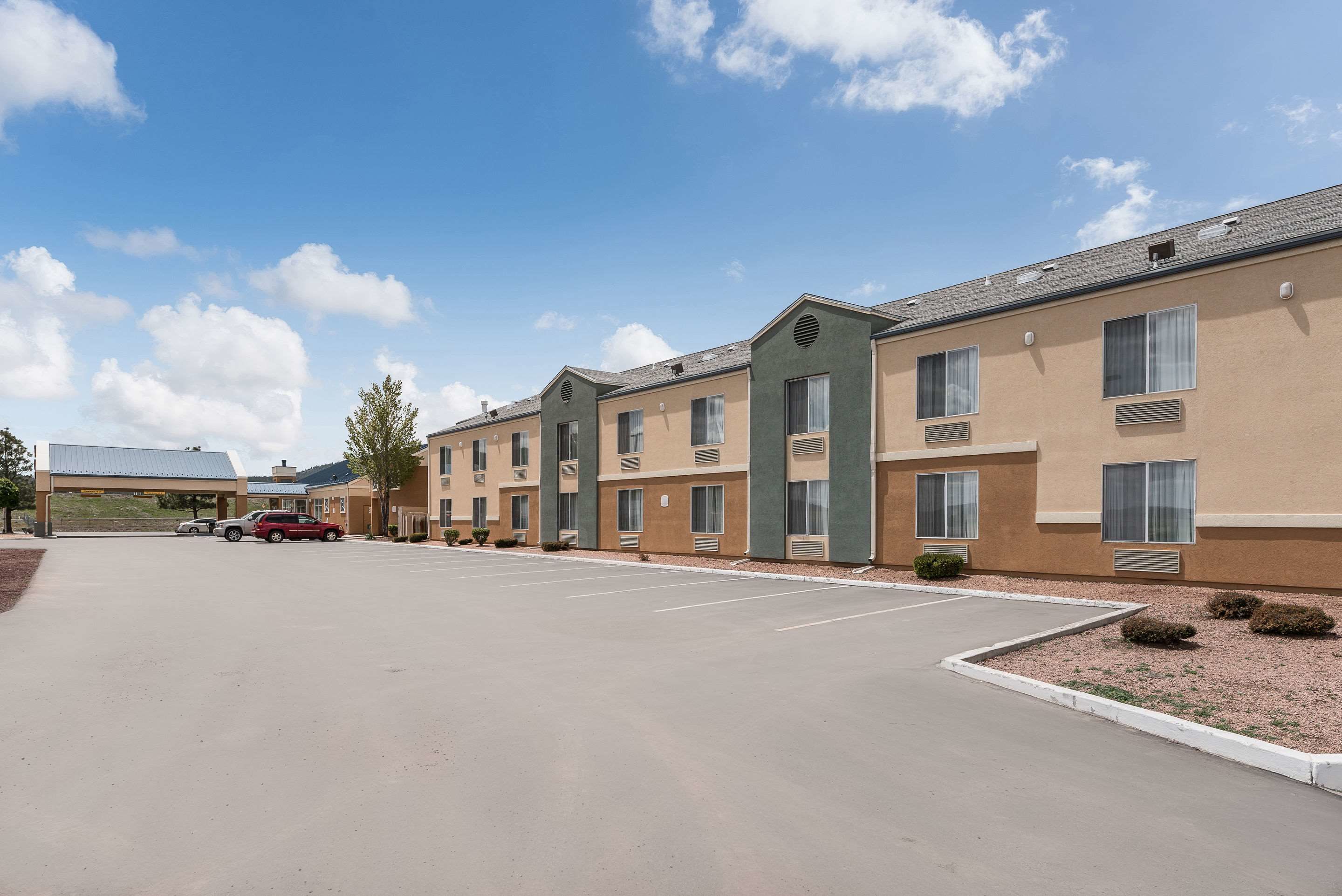 A hotel with multiple buildings, a parking lot, and a few cars.