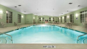 A large indoor pool with clear water, surrounded by green walls and multiple windows. - Ramada by Wyndham Williams/Grand Canyon Area (Williams)