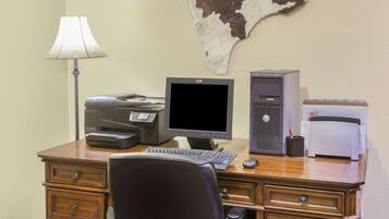 A wooden desk with a computer setup including a monitor, keyboard, and printer.