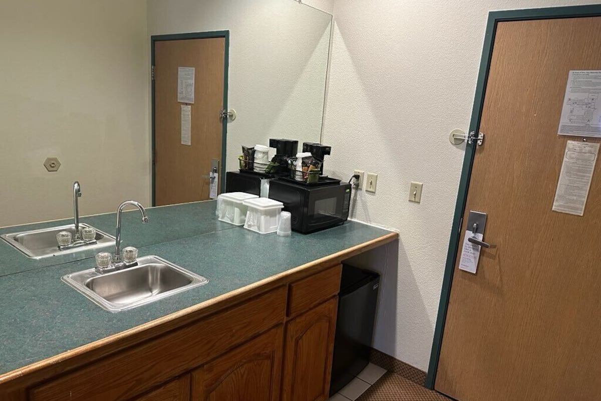 A kitchenette with a sink, a coffee maker, and a trash bin.