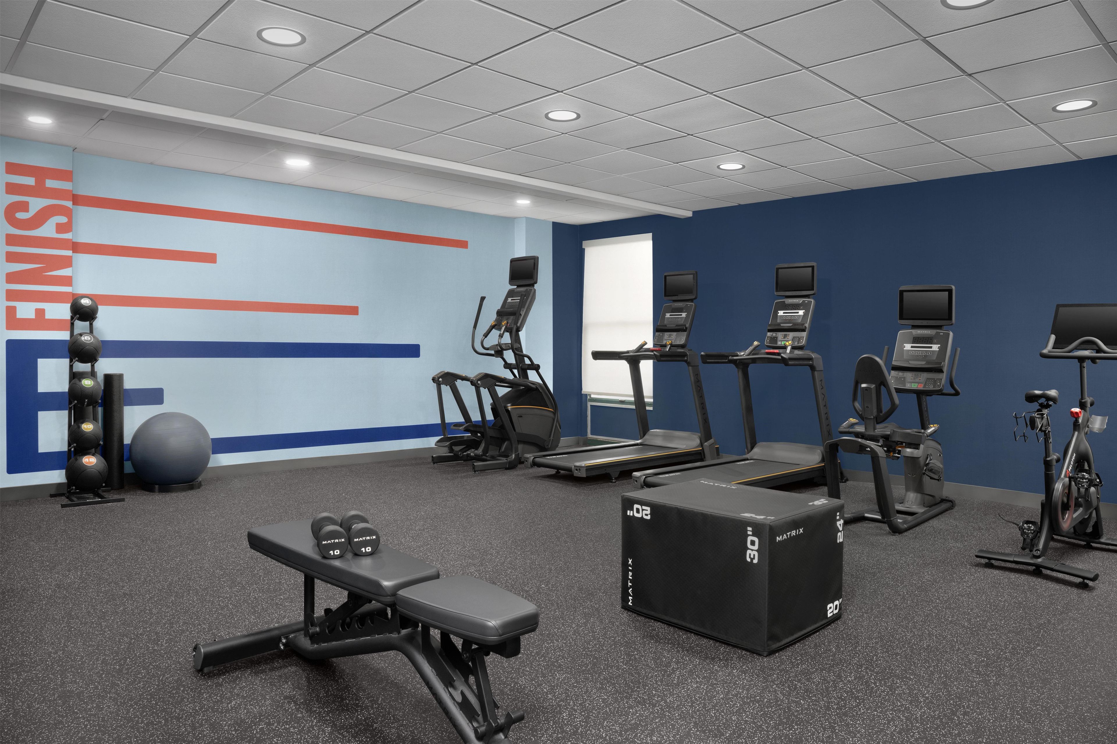 A gym with treadmills, elliptical machines, a bench press, and weightlifting equipment.