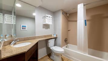 Un baño moderno con lavamanos de granito, inodoro y ducha a ras de suelo con cortina.