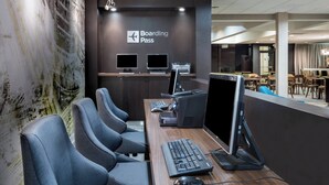 Un área de recepción moderna con un letrero que dice 'Boarding Pass', estaciones de computadoras y asientos.