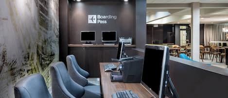 A modern check-in area with a 'Boarding Pass' sign, computer stations, and seating.