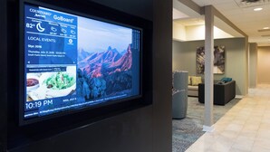 Pantalla digital en el vestíbulo de un hotel con vistas a la montaña, un sofá y un cuadro en la pared.