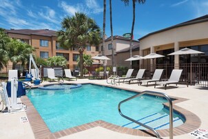Una piscina al aire libre, sombrillas, sillones reclinables de piscina