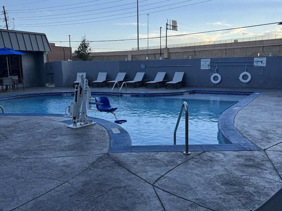 Una piscina con sillas de descanso, un puesto de socorrista y un flotador.