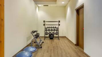A hallway with a weightlifting area, including dumbbells and a bench press.