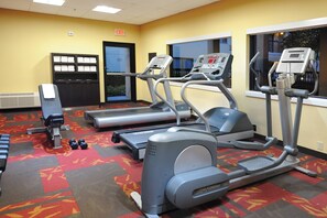 Ein Fitnessstudio mit Laufbändern, Crosstrainern und Kurzhanteln.