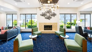 A spacious lobby with a fireplace, seating area, and large windows offering views of the outdoors.