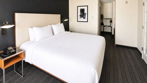 A hotel room with a large bed, a bedside table with a lamp, a phone, and a picture on the wall.