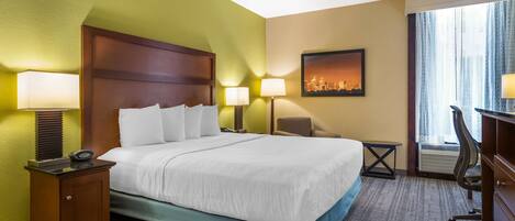A hotel room with a large bed, two bedside lamps, a desk, and a chair.