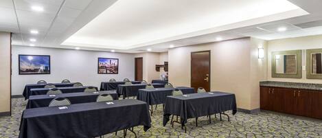 A conference room with tables, chairs, and a patterned carpet.