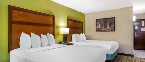 A hotel room with two beds, a green wall, a framed picture, and a carpeted floor.