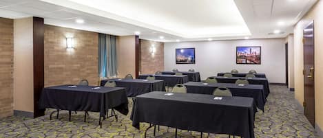 Un salón de conferencias con mesas y sillas, una alfombra estampada e iluminación en la pared.