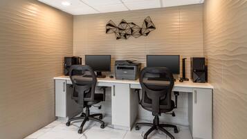 Un espace de bureau moderne comprenant deux bureaux, chacun équipé d’un ordinateur et d’une imprimante. On y trouve également deux chaises de bureau et un élément décoratif fixé au mur, au-dessus des bureaux.