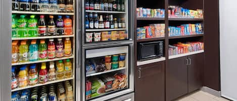 Máquina expendedora llena de diversas bebidas y aperitivos, como refrescos, jugos y alimentos envasados.