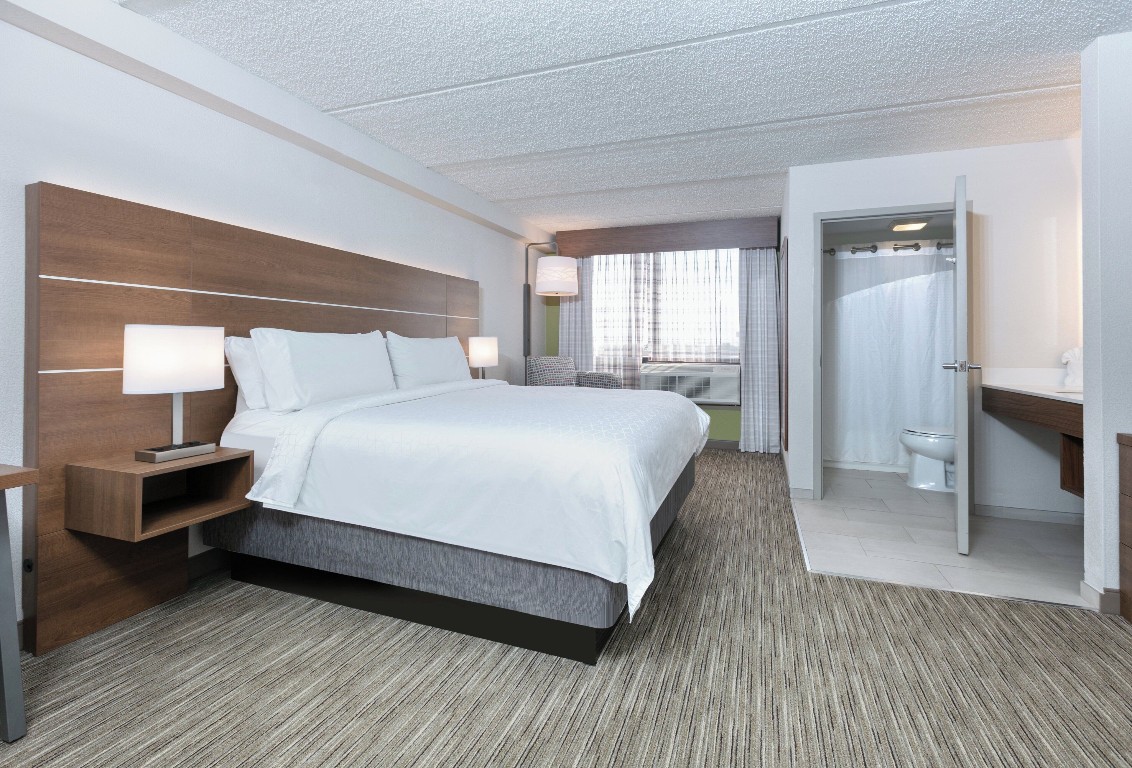 A hotel room with a large bed, bedside tables, a desk, and a bathroom.