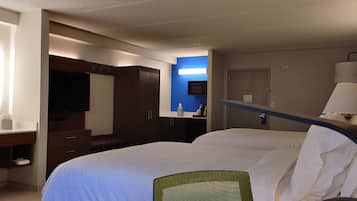 A hotel room with a bed, a desk, a television, a microwave, and a door.