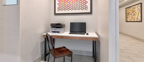 Una habitación de hotel con escritorio, silla y una obra de arte abstracto enmarcada en la pared.