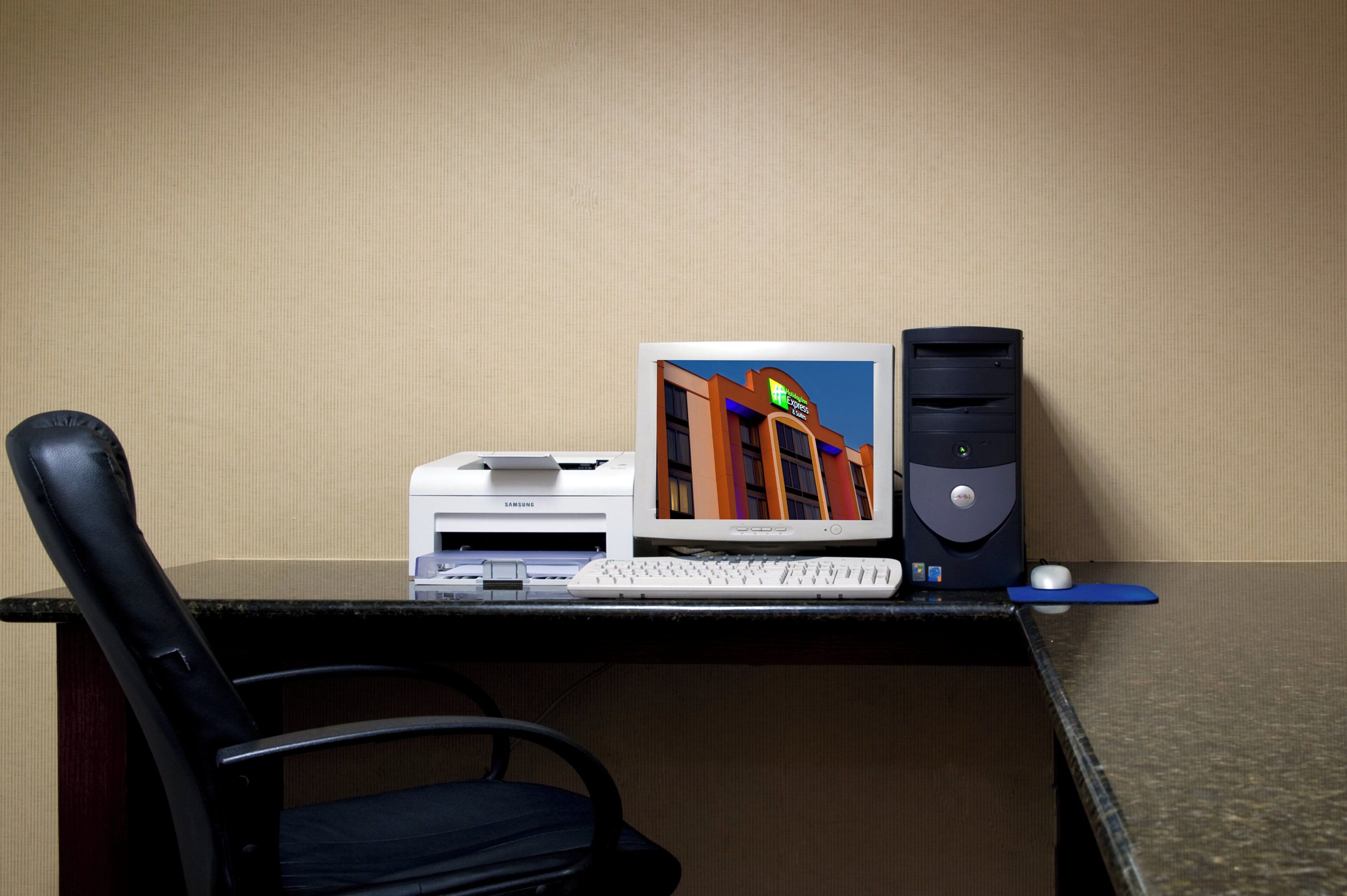 Escritorio de habitación de hotel con una computadora de escritorio, una impresora y una silla.