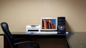 Escritorio de habitación de hotel con una computadora de escritorio, una impresora y una silla.