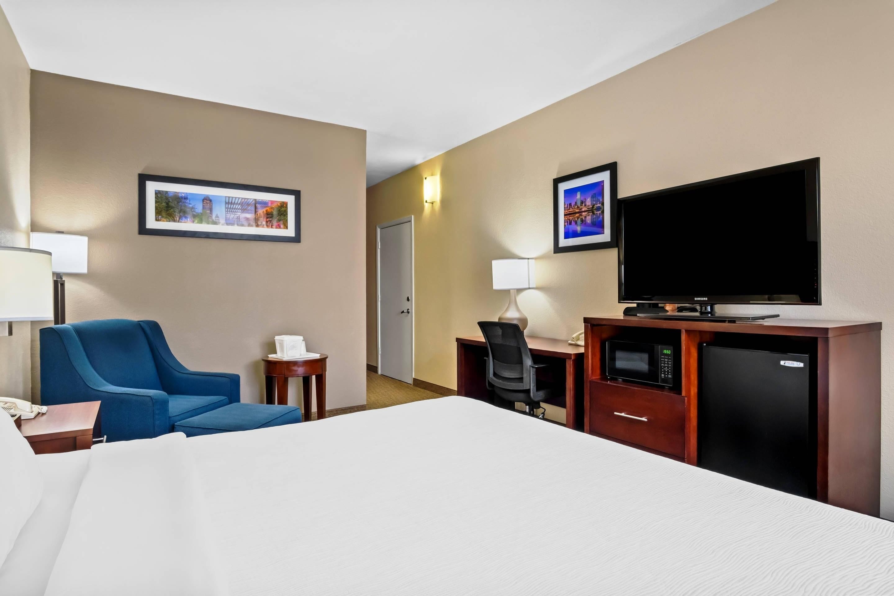 A hotel room with a bed, a desk with a computer, a television, and a microwave.