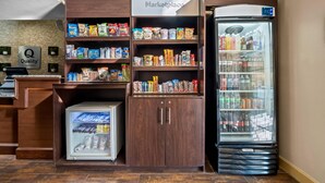 Un hall de hotel con un quiosco de autoservicio, un refrigerador y un letrero que dice 'Marketplace'.