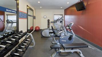 A gym with treadmills, dumbbells, and exercise balls.