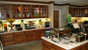A spacious kitchen with wooden cabinets, a large island with a grill, and various kitchen appliances. - Hampton Inn San Angelo (San Angelo)
