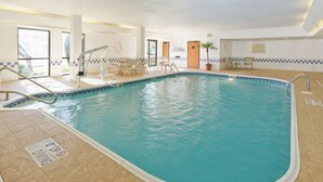 An indoor swimming pool with a tiled deck, a diving board, and a seating area with chairs and tables. - Hampton Inn San Angelo (San Angelo)