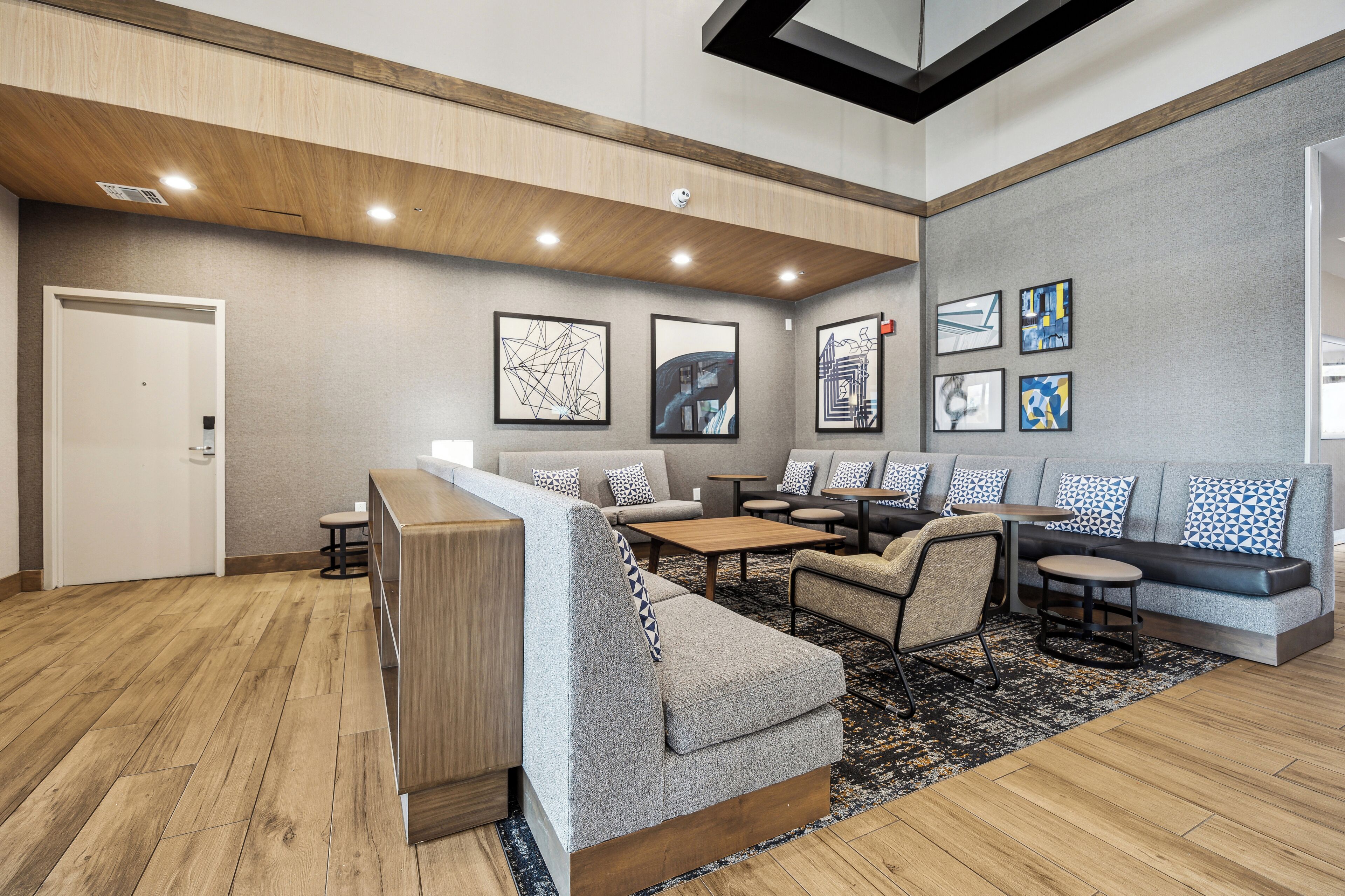 A modern lobby with a reception desk, seating area, and artwork on the walls.